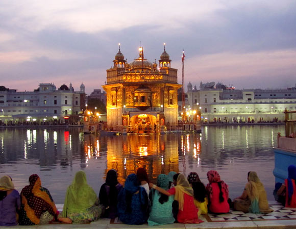Indian women sat by a lake overlooking a temple in Amritsar_2
