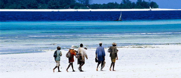 fishermen walking along a beach in Zanzibar Tanzania