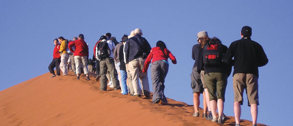 A group of tourists walking up a sand dune