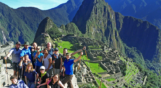 a group of hikers smiling in front of Machu Picchu